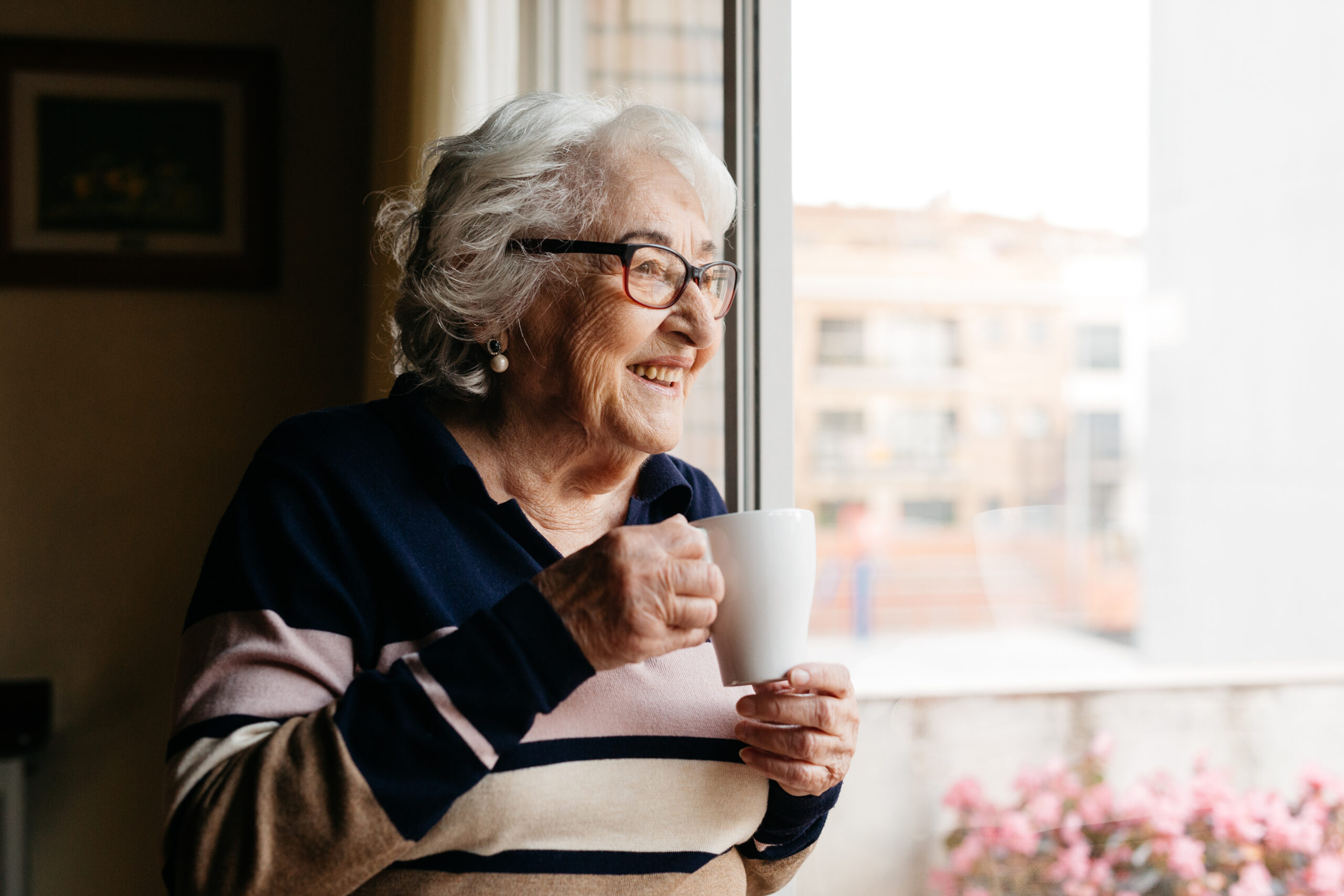 Elderly woman drinking coffe at home. Smiling senior at University Village 55+ apartments community